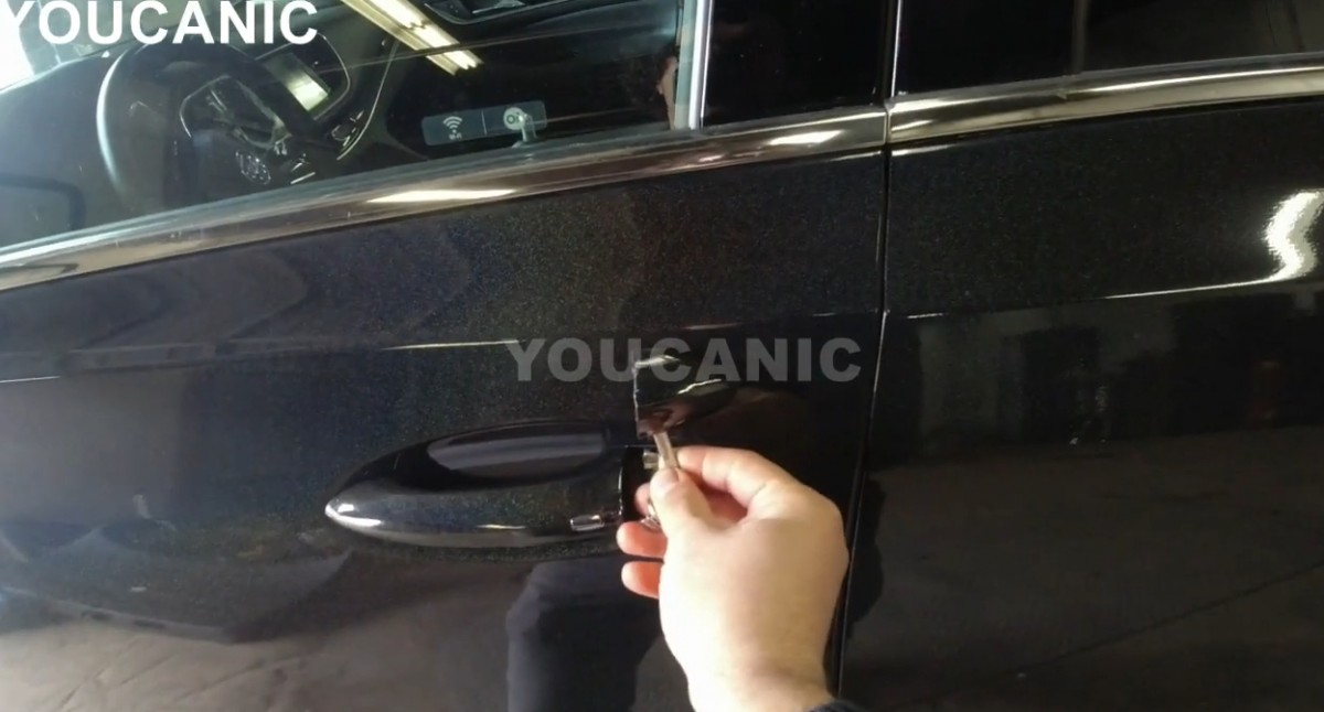 Removing the cap on the door handle to expose the lock cylinder.