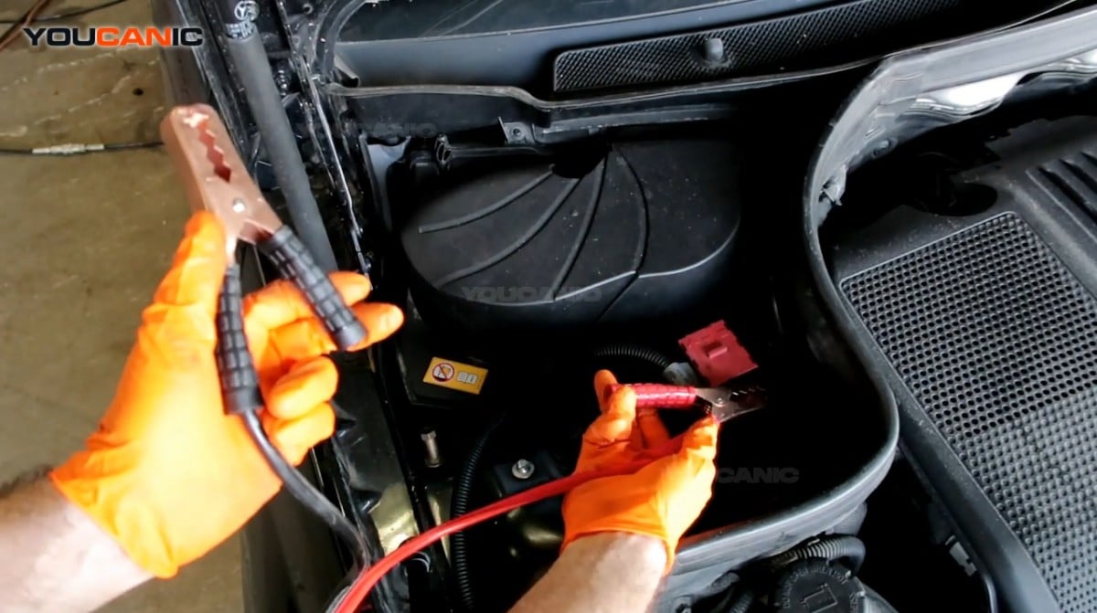 Connecting the red jumper cable to the positive terminal of the battery.