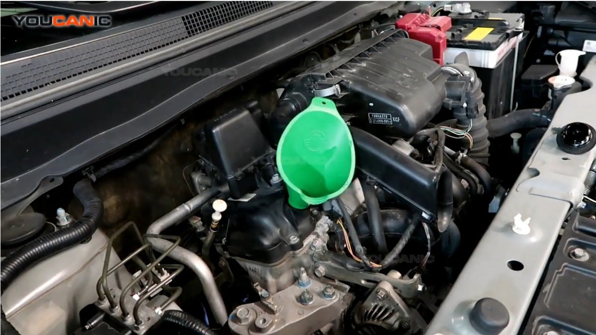 Adding engine oil to the Mitsubishi Mirage G4 using a funnel.
