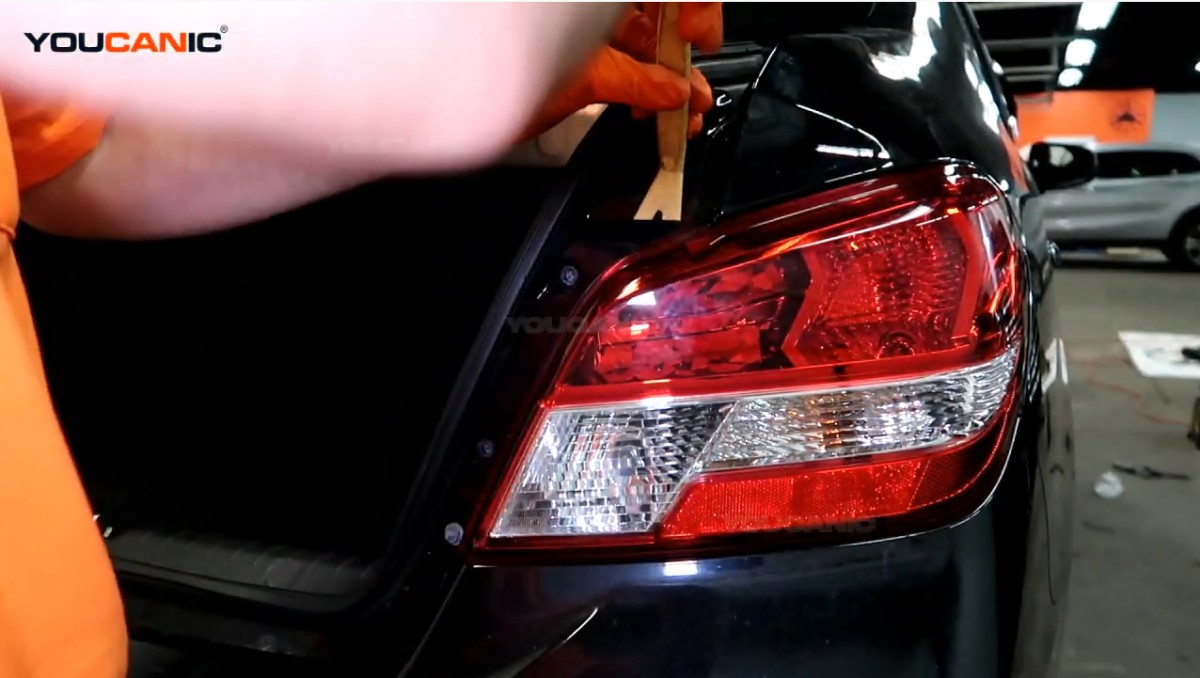 Poping out the tail light using a prying tool.