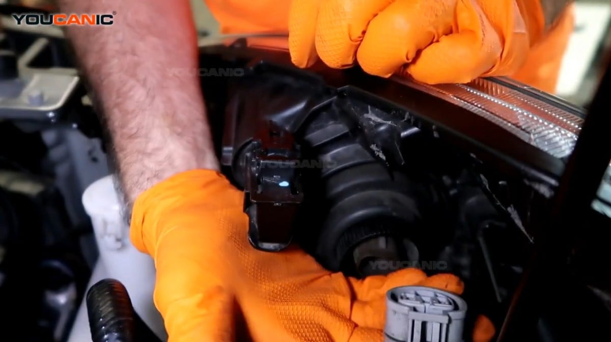 Removing the headlight connector of the Mitsubishi Mirage.
