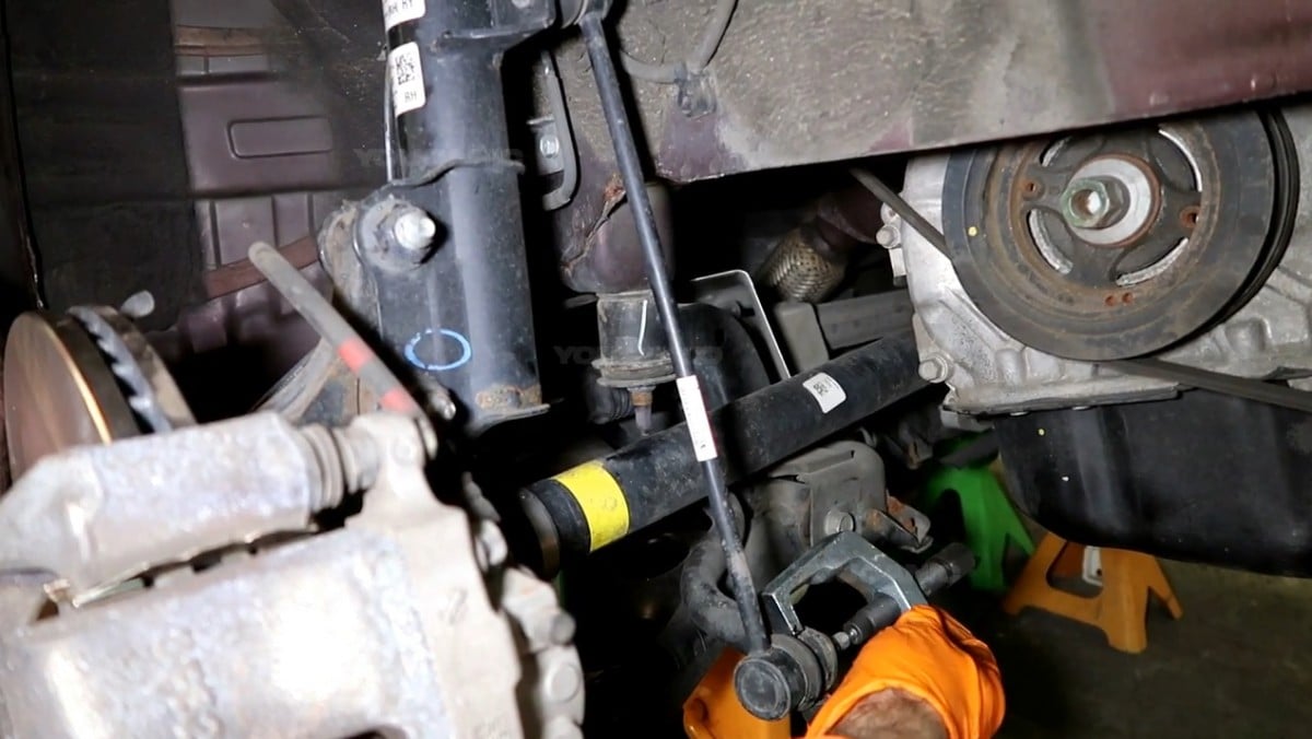 Removing the sway bar link from the vehicle.