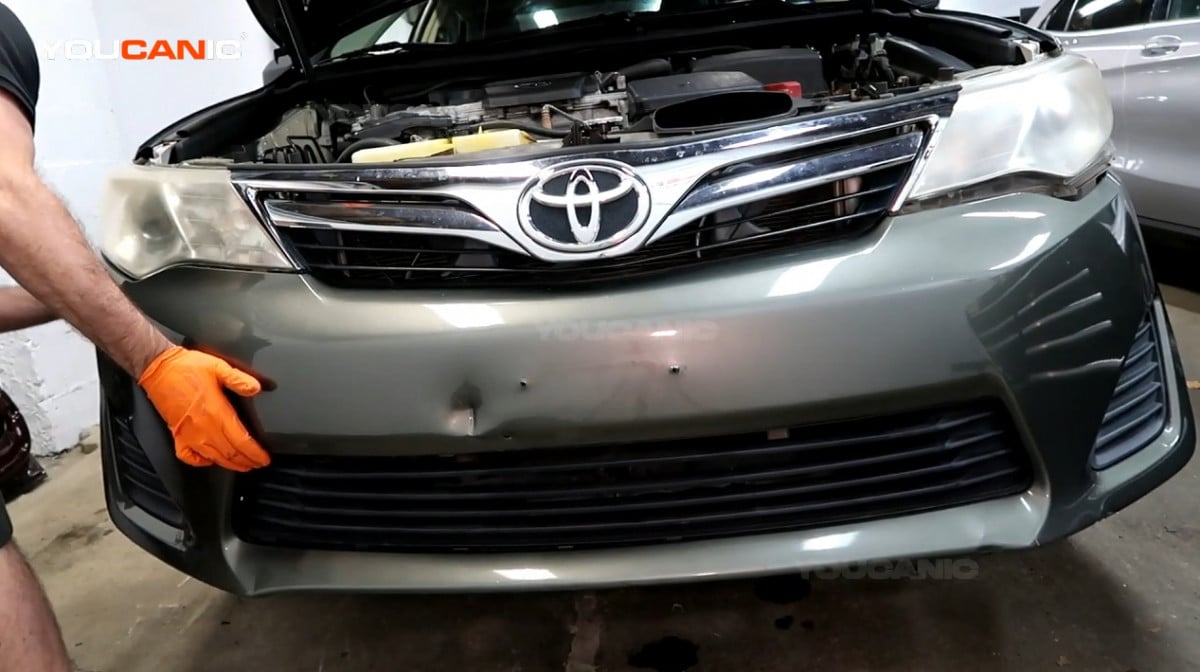 Installing the new front bumper of the Toyota Camry.