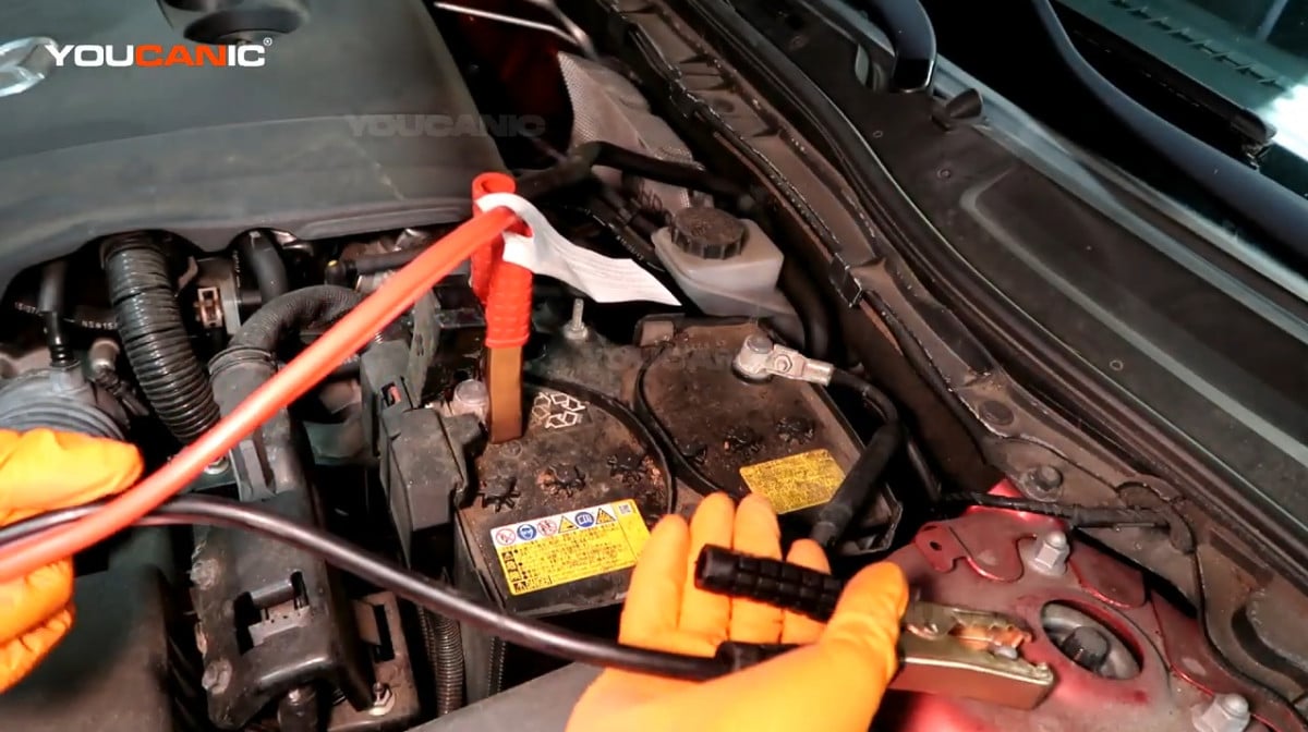 Connecting the black jumper cable to the ground terminal of the vehicle.