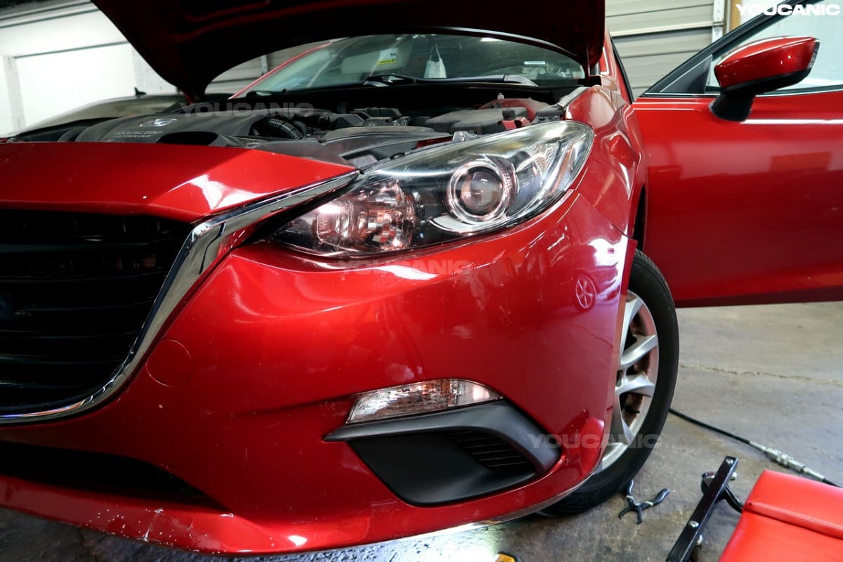 Opening the hood of the Mazda 3.