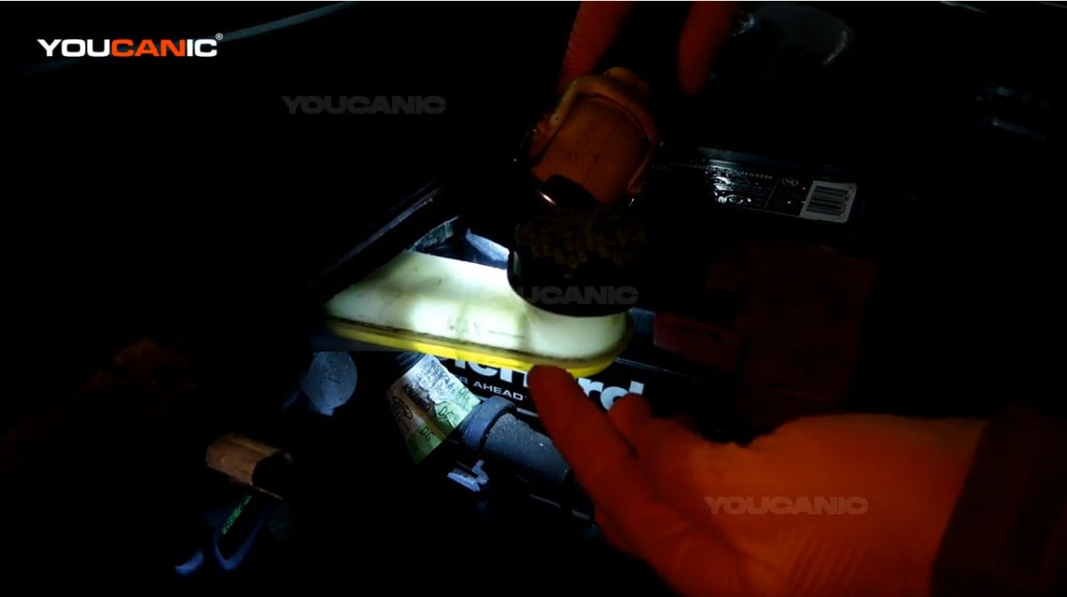 Checking the brake fluid level using a flashlight.
