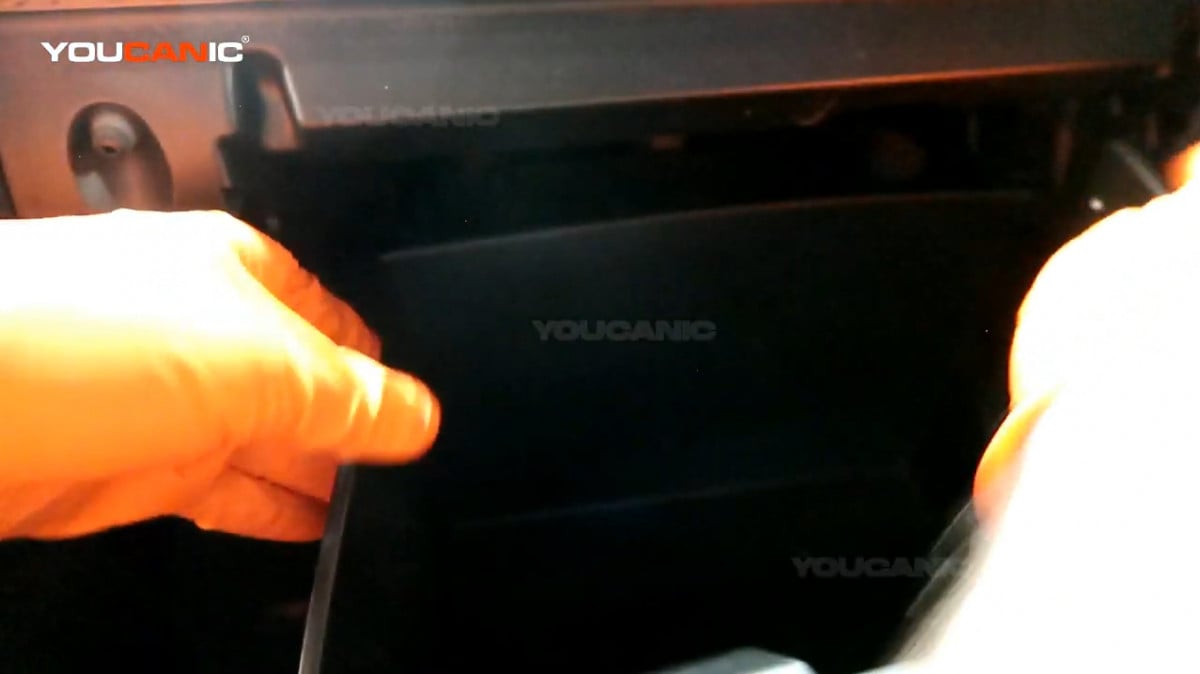 Pressing the side of the glove box to unlock the side tabs.