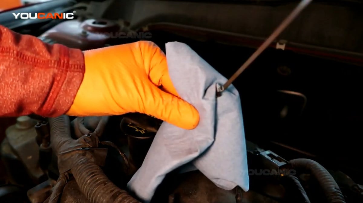 Wiping the oil dipstick with cloth.