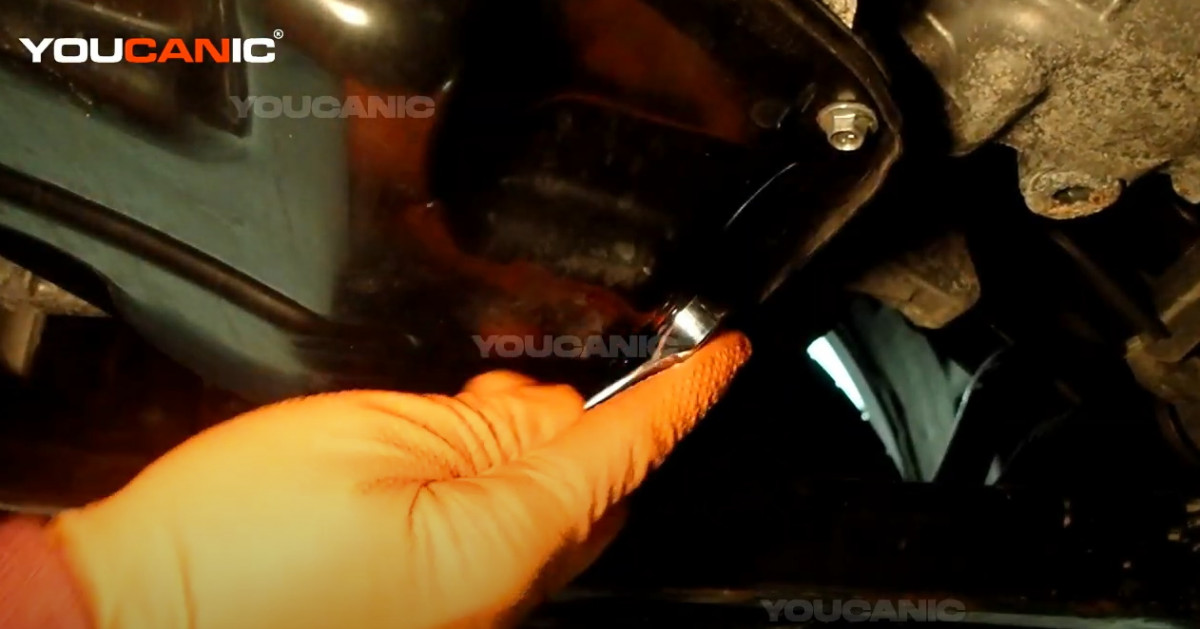 Loosening the oil drain plug of the Nissan Rogue Sport.