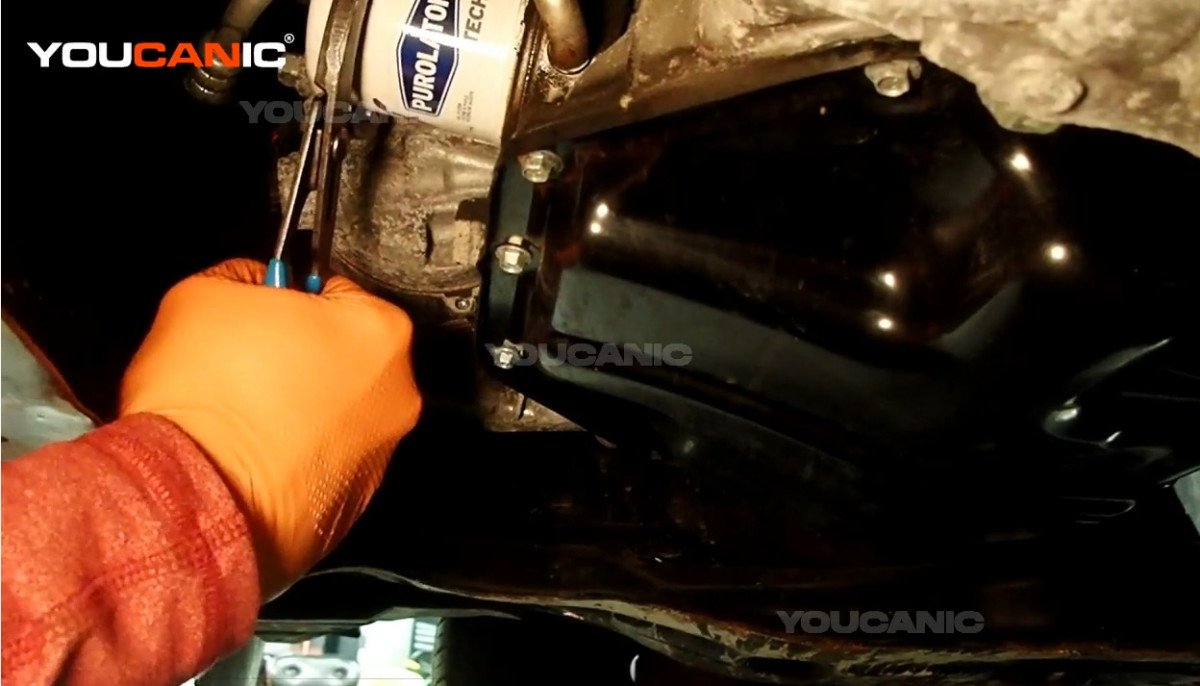 Loosening the oil filter of the Nissan Rogue Sport.