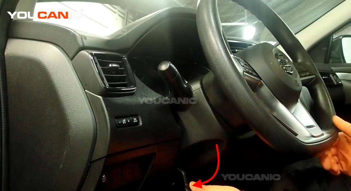 Unlocking the steering wheel adjust lever of the Nissan Rogue Sport.