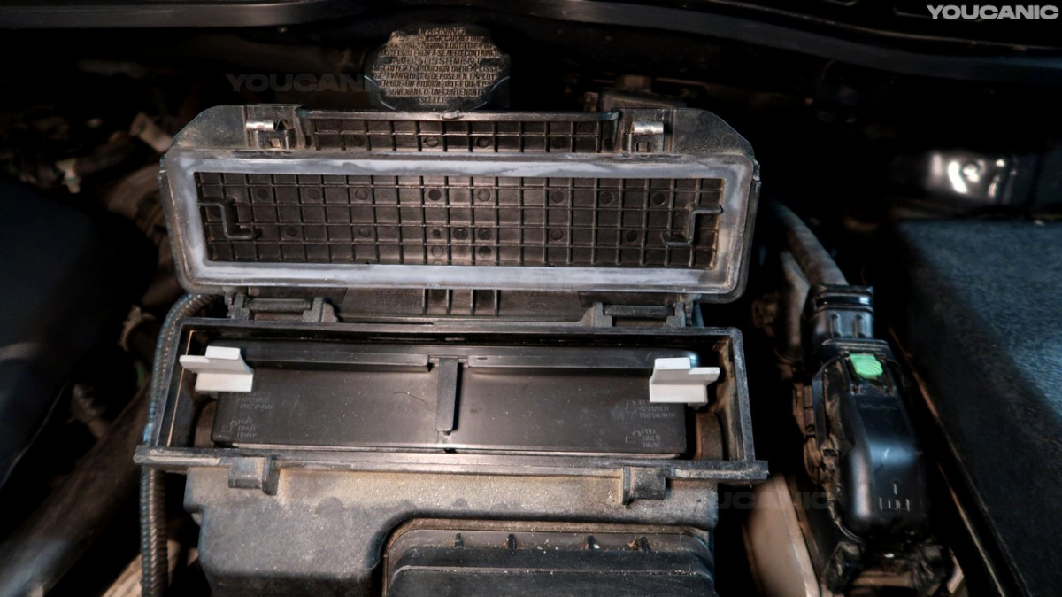 Opening the air filter housing of the Kia Sedona.